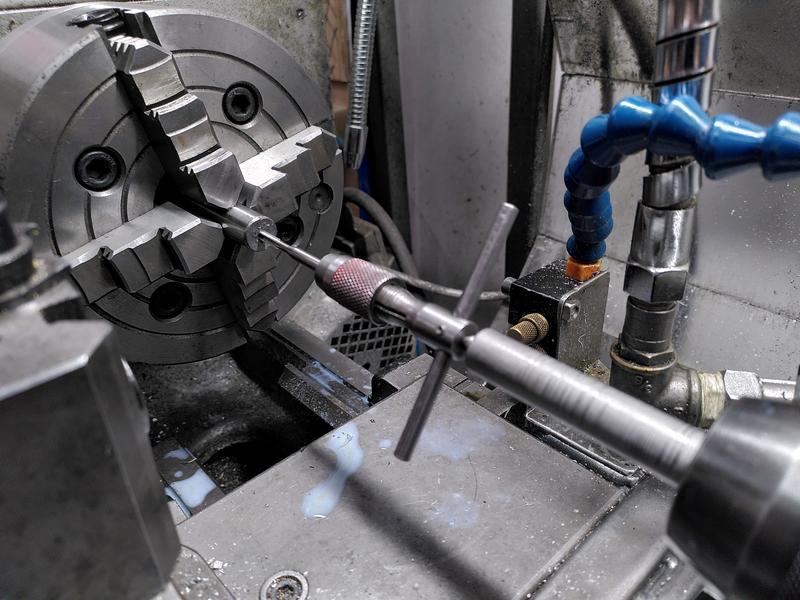 A piece of steel held in a 4 jaw chuck on the lathe. A tap is held in
tapping wrench tapping a thread in the centre of the part. The tap is held
by a sprint loaded tap follower in the tail stock.