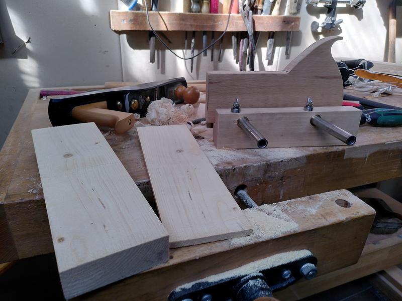 In the four ground a piece of 2x4 pine sits with a thin board next to it
that has been sawn off the 2x4. In the background on the left a stanley
sweetheart 62 low angle jack plane lays on its side. On the right the
kerfing plane I've been making sits, fence side to the camera.